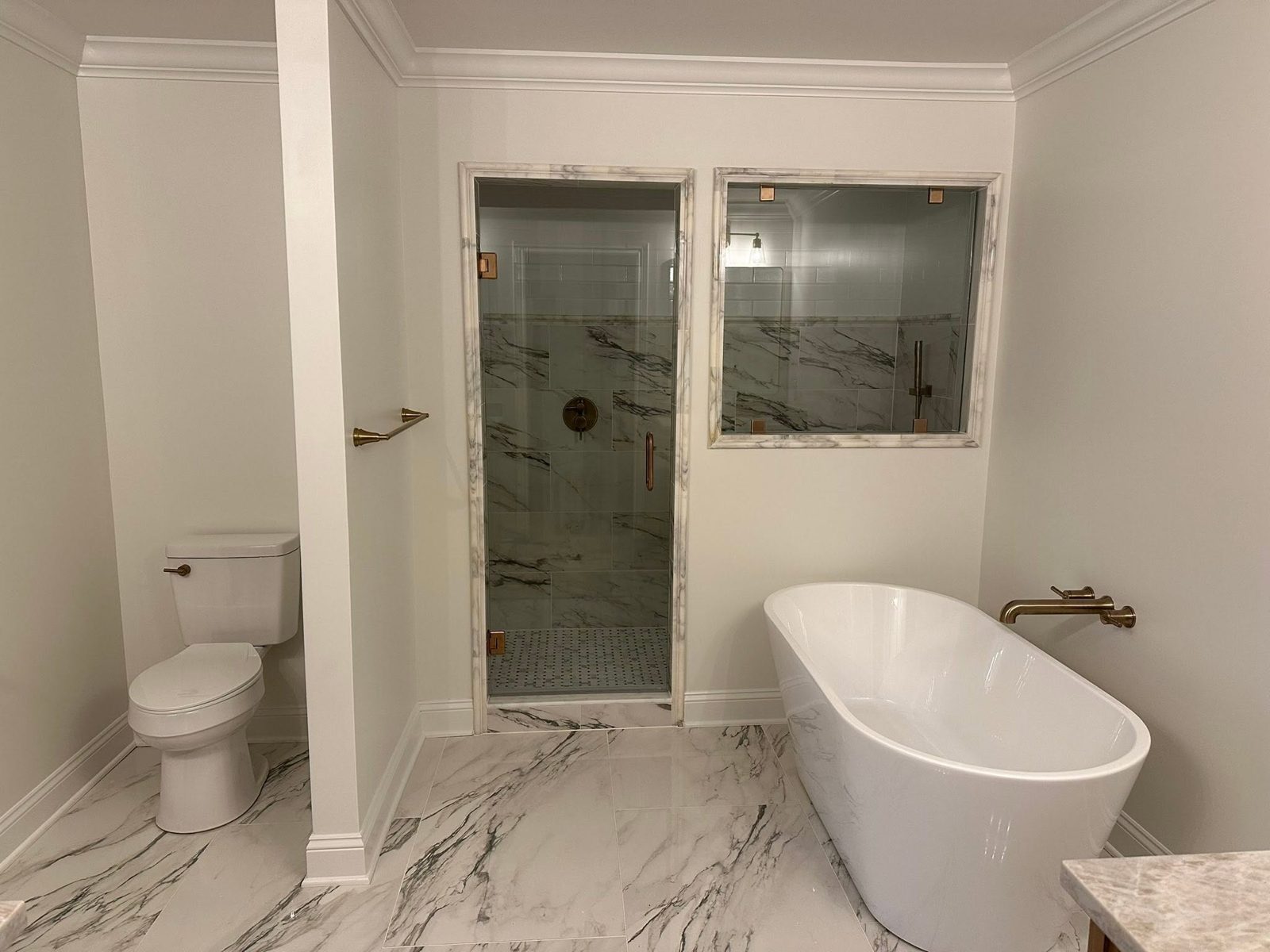 New construction primary bathroom with marble surround and soaking tub