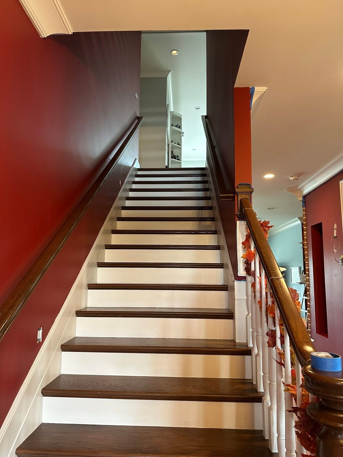 Red accent hallway with white painted stair rail and trim